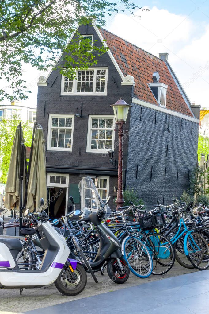Netherlands. Sunny spring day in Amsterdam. Bicycle parking in front of a sloping typical Dutch house