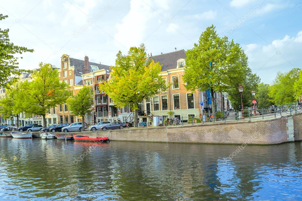 Netherlands. Spring day on the Amsterdam Canal. Boats moored on the water and cars on the embankment