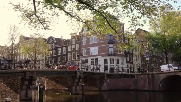 オランダだ 橋やアムステルダムの典型的な家 晴れた朝と軽自動車と自転車の交通 — ストック動画