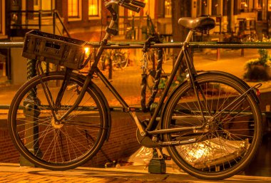 Hollanda 'da. Gece Amsterdam. Bavul sepeti olan bisiklet kanal çitlerinin oraya park edilmiş ve hırsızlığa karşı bir zincirle korunuyor.