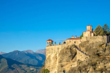 Yunanistan. Meteora 'da açık bir yaz günü. Bir dağ vadisine karşı kırmızı çatıları olan ağaç ve kaya manastırı