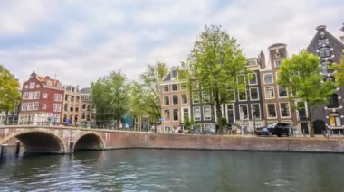 Hollanda 'da. Amsterdam Kanalı 'nda akşam. Eski taş köprü ve setin üzerindeki tipik evler. Su ve sokak trafiği. Zaman aşımı