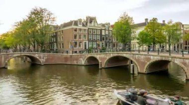 Netherlands. Summer evening on the canals of Amsterdam. Busy movement of boats on the water and cars, bicycles and people on the bridges. Time lapse