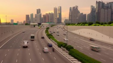 Sunset in Singapore. Traffic on a multi-lane highway against the backdrop of many skyscrapers