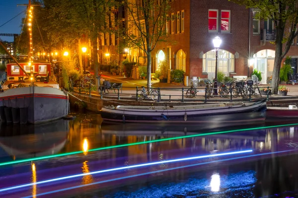 Netherlands. Summer night in Amsterdam. Canal embankment with residential barges and bicycles