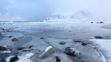 Norveç 'te kış günü. Geniş deniz plajı ve kayalık dağlar. Uzun dalga