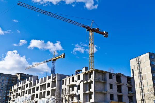 Building crane on the background of blue sky and of the house under construction — Stock Photo, Image