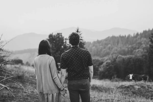 若い恋人のカップルが手を取り合い 森の中で美しい景色を楽しむことの後部ビュー 山を背景に カルパティア人 ウクライナ 白黒写真 — ストック写真