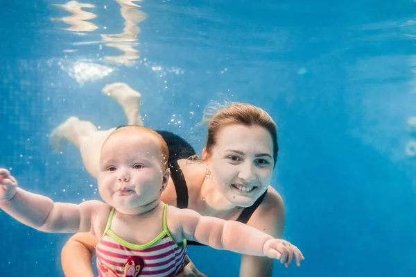 母は娘がプールで水の下で泳いで 水に浸かっている保持しています 潜水赤ちゃん 幼児の水泳を学ぶ 若いですお母さんや水泳インストラクターと幸せな女の子 — ストック写真