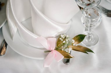 Servis, kurma masası. Gümüş çatal bıçaklı tabak, keten peçete altın dallı yeşilliklerle süslenmiş. Düğün masası dekorasyonu. Kapat..