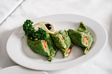 Masadaki beyaz tabakta kırmızı havyarlı ıspanaklı krep. Lezzetli bir yemek. Şenlik masasında yemek servisi yapıyor. Düğün yemeğinde ziyafet masasında yemek..