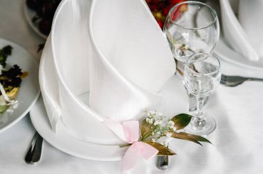 Servis, kurma masası. Gümüş çatal bıçaklı tabak, keten peçete altın dallı yeşilliklerle süslenmiş. Düğün masası dekorasyonu. Kapat..