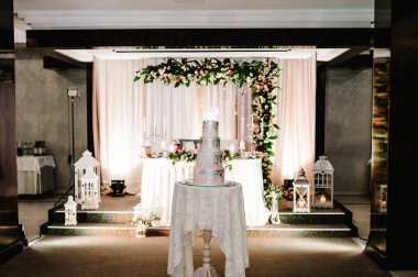 Pembe çiçekli beyaz düğün pastası ve pastalı şenlik masasında yeşiller. Pastayı kapat. Güzel masa..