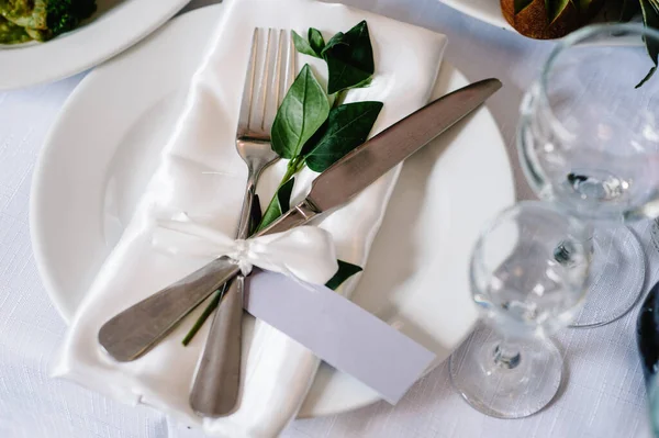 Servis, kurma masası. İki tabak ve gümüş çatal bıçak takımı keten peçete pembe kurdeleler ve dallarla süslenmiş. Düğün masası dekorasyonu. Sanat eserleri. Düz yat. Üst Manzara. Kapat..