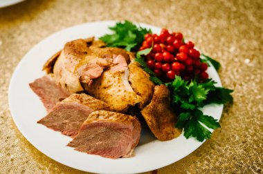Otlu tavuk eti. Beyaz tabakta tavuk göğsü dilimleri, masada izole..