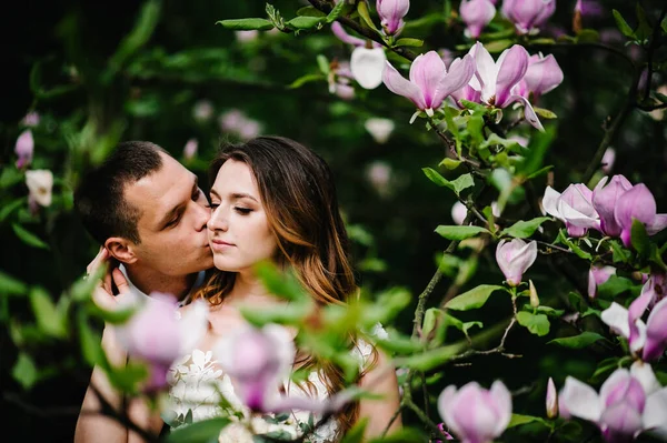 Hochzeitspaar Vor Rosa Und Lila Blüten Aus Magnolie Und Grün — Stockfoto