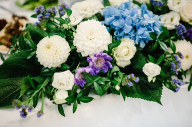 Çiçek ve yeşillik kompozisyonu ile süslenmiş şölen masası, şölen salonunda mumlar. Yeni evliler düğün ziyafeti alanında toplandı..