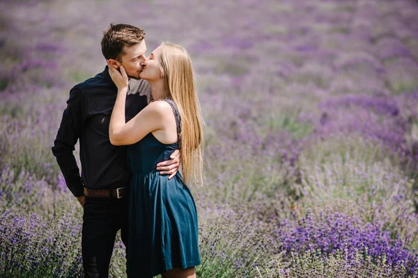 Lovely young couple in love in purple lavender field kissing and have romantic time. Man and woman in the flower fields. Honeymoon trip. Newly married. Happy couple travel. Lavender meadows.