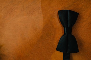 Siyah papyon kahverengi arka planda izole edilmiş. Üst manzara, düz uzanma.