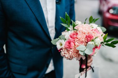 Çiçek buketi tutan bir adamın elleri. Kadınlar Günü 'ne hediye. Çiçek tasarımı. Hediye buketi 8 Mart 'ta.