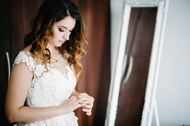 Gelinlik giymiş çekici bir gelin altın bir nişan yüzüğü takıyor ve düzeltiyor. Gelinin Hazırlıkları. Düğün Sabahı.