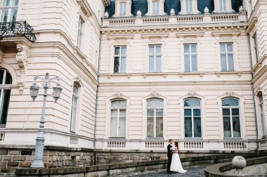 Damat ve gelinlik giymiş gelinin portresi antik restore edilmiş mimari, eski bina, dışarıdaki eski ev, klasik sarayın yanında duruyor..