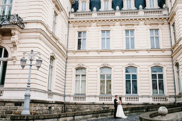 Damat ve gelinlik giymiş gelinin portresi antik restore edilmiş mimari, eski bina, dışarıdaki eski ev, klasik sarayın yanında duruyor..