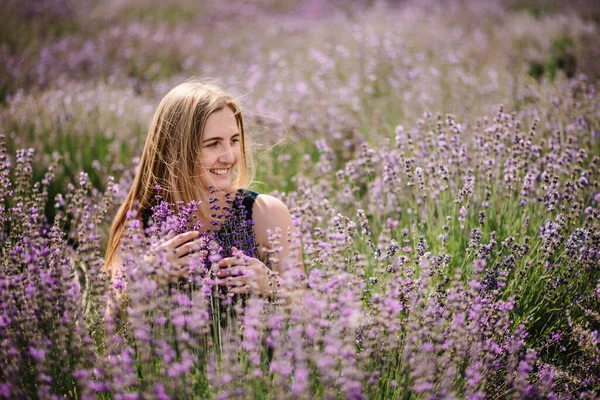 紫のラベンダー畑に身を包んだ美しい女の子 美しい女性がラベンダー畑を歩いています ラベンダーを集めろ 花のグレード 夏の自然をお楽しみください 天然化粧品とエコメイクのコンセプト — ストック写真