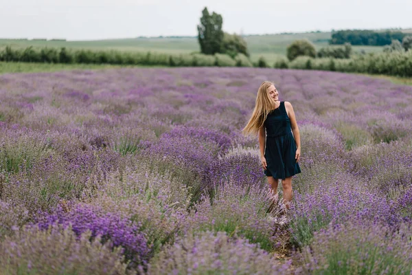 穿着衣服站在紫色薰衣草地里 长发飘扬的漂亮姑娘 日落时 美丽的女人在薰衣草田里散步时很滑稽 尽情欣赏花香 享受夏日的自然 — 图库照片