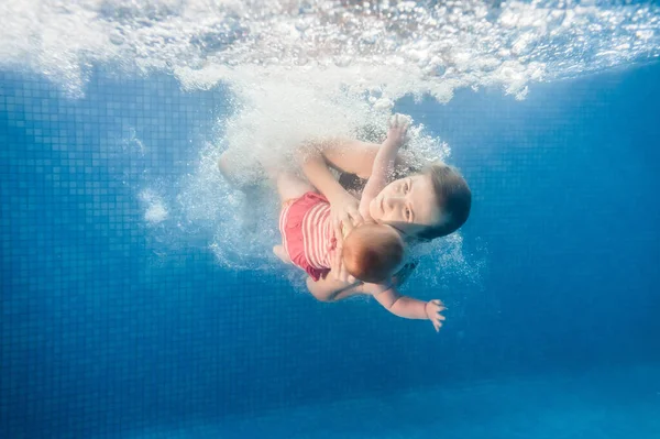 母は娘がプールで水の下で泳いで 水に浸かっている保持しています 潜水赤ちゃん 幼児の水泳を学ぶ 若いですお母さんや水泳インストラクターと幸せな女の子 — ストック写真