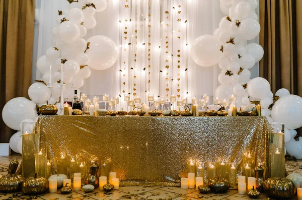 Table setting for wedding. Decorated arch for wedding ceremony. White balloons, candles, autumn leaves and small pumpkins. Autumn location and Halloween decor.