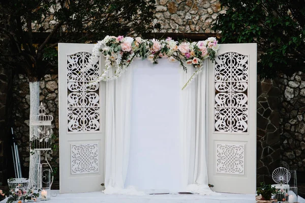 Wedding decorations in luxury ceremony. Arch for wedding ceremony a is decorated with flowers and greens, greenery.  wedding decor in the backyard banquet area.