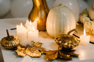 Decorated table for wedding. White balloons, candles, autumn leaves and small pumpkins. Autumn location and Halloween decor. Setting.