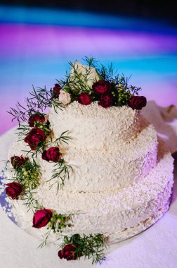 Düğün pastası. Masada çiçeklerle süslenmiş klasik katmanlı beyaz pasta..
