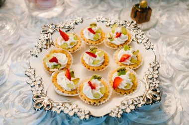 Güzel masa. Böğürtlenli kremalı kek ve kek. Şekerli masa, şeker, açık büfe. Düğün için parti malzemeleri için tatlı masası. Kapat..