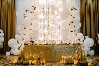 Table setting for wedding. Decorated arch for wedding ceremony. White balloons, candles, autumn leaves and small pumpkins. Autumn location and Halloween decor.