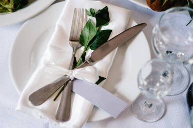 Servis, kurma masası. İki tabak ve gümüş çatal bıçak takımı keten peçete pembe kurdeleler ve dallarla süslenmiş. Düğün masası dekorasyonu. Sanat eserleri. Düz yat. Üst Manzara. Kapat..