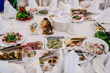 Yiyecekler. Tabaklarla dolu bir şölen masası. Bulaşık. Yan görünüm.