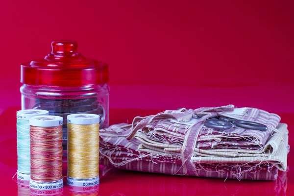 Tarro de vidrio, carretes y tijeras aisladas en rojo . — Foto de Stock