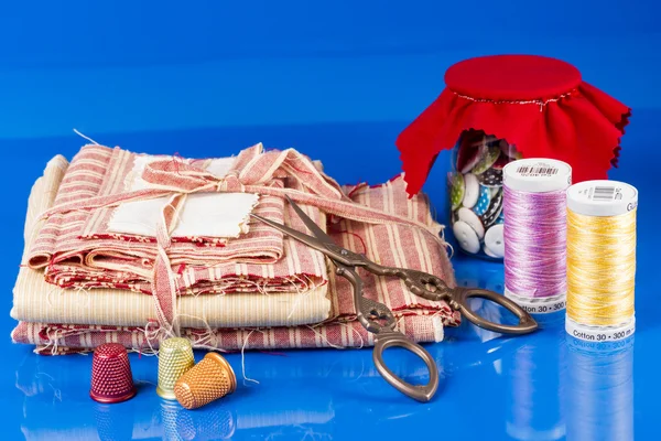 Glass Jar, Scissors, Thimbles and Spools Isolated on Blue. — Stock Photo, Image