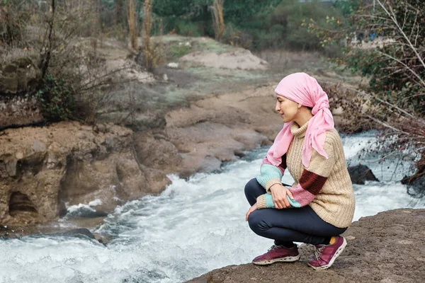 young woman with cancer contemplating a river
