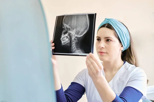 woman in the dental clinic and looking at the X-ray image check the patient\'s teeth.