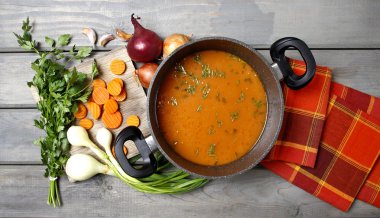 Top view on pot of tomato soup and fresh vegetables on old woode clipart