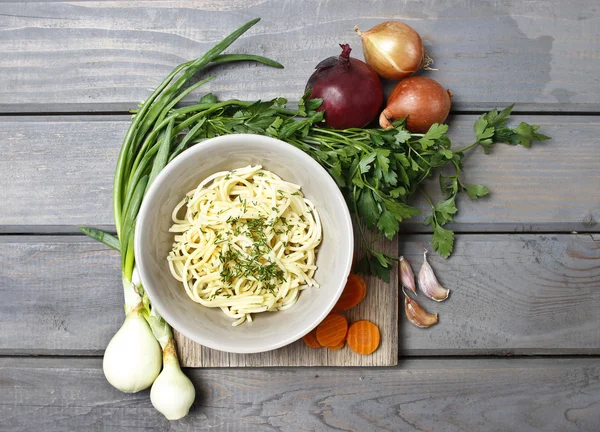 Vue de dessus sur bol de spaghettis et légumes frais sur vieux bois — Photo