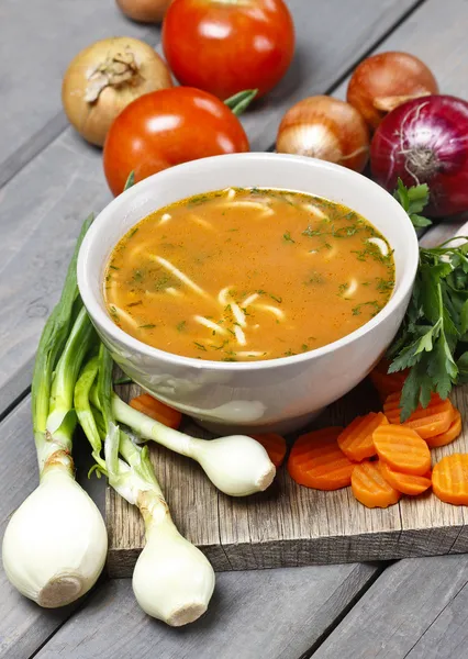 Tigela de sopa de tomate e legumes frescos na velha mesa de madeira — Fotografia de Stock