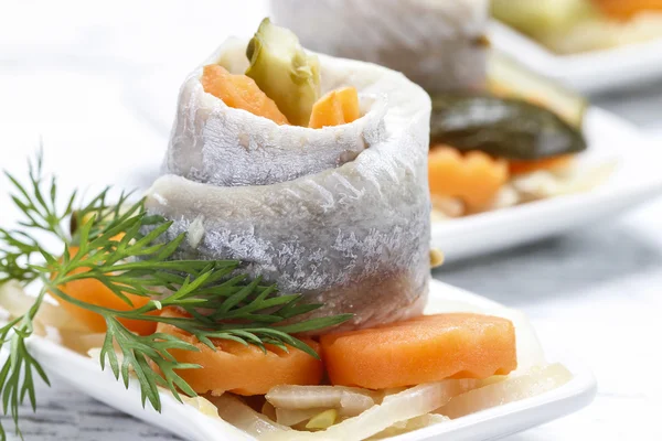 Rollos de arenque en escabeche con verduras en mesa de madera —  Fotos de Stock