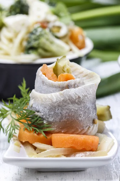 Ingelegde haringen rollen met groenten op houten tafel — Stockfoto