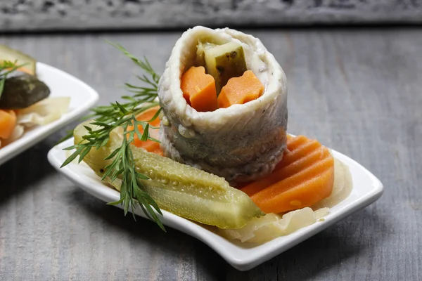 Pickled herring rolls with vegetables on wooden table — Stock Photo, Image