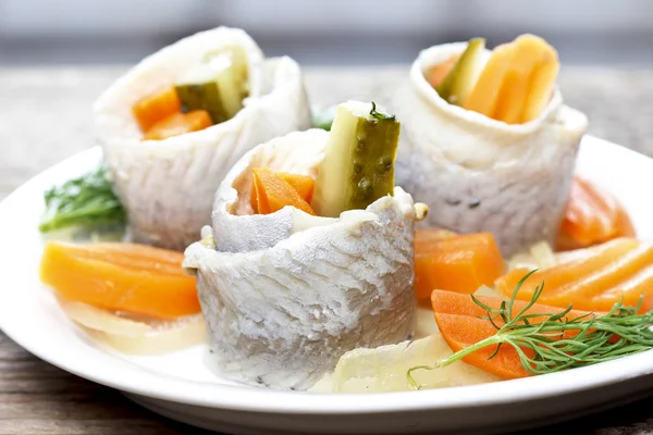 Rollos de arenque en escabeche con verduras en mesa de madera —  Fotos de Stock