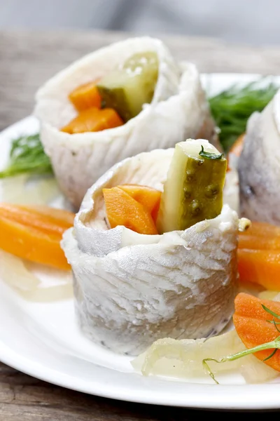 Pickled herring rolls with vegetables on wooden table — Stock Photo, Image